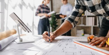 Ofiste dizüstü bilgisayar kullanarak yeni projenin taslağı üzerinde çalışan mühendisler