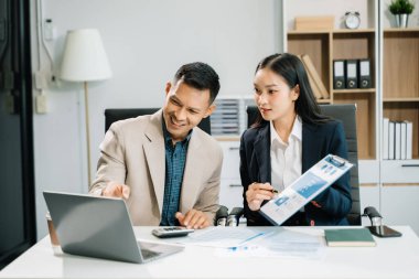 Modern ofiste bilgisayar üzerinde çalışan iki genç iş arkadaşı.