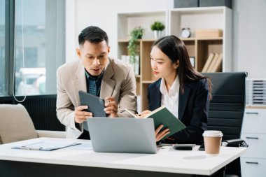 Ofiste dijital tablet ve laptop kullanan iki Asyalı iş adamı