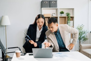 Ofiste dizüstü bilgisayar kullanan iki Asyalı iş adamı.