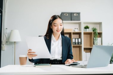 Ofiste çalışırken dizüstü bilgisayar ve hesap makinesi kullanan kadın girişimci 