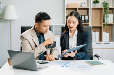 Ofiste dizüstü bilgisayar kullanan iki Asyalı iş adamı.