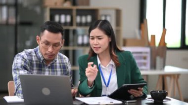 Asyalı işadamı sunar ve yeni projeyi bilgisayar ve dijital tablet kullanarak açıklar. Modern ofis odasında çalışırken takım çalışması, finansal pazarlama ekibi..