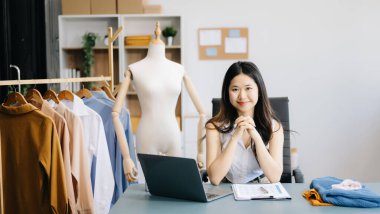  Moda tasarımcısının masasındaki Asyalı genç kadın stüdyoda çalışıyor.