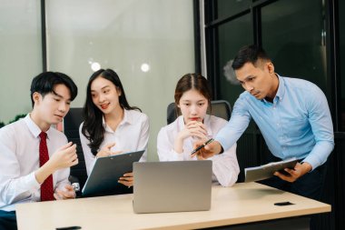 Ofiste yeni bir projede işbirliği yapan iş adamları. Ofiste dizüstü bilgisayar kullanan bir grup iş adamı..