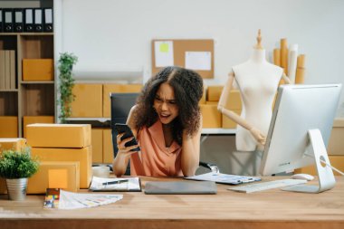 Kızgın genç işletme sahibi internet üzerinden akıllı telefondan müşteriye teslimat siparişlerini kontrol ediyor. 