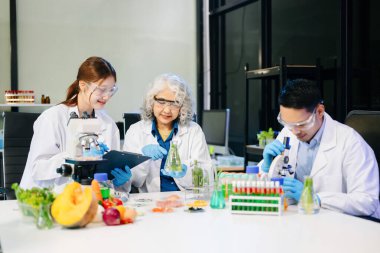 Laboratuvar önlüklü gıda bilimcileri, numuneleri test ediyorlar ve modern bir laboratuvarda gıda güvenliğini ve kalitesini analiz ediyorlar. 