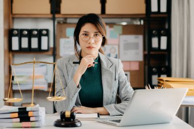 Asyalı kadın avukat mahkeme salonunda dizüstü bilgisayarla çalışıyor.