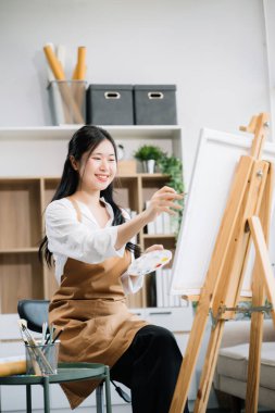 Sanat atölyesinde resim yapan Asyalı kadın ressam, boya malzemeleri, yağ boyaları, sanat stüdyosunda yaratıcı alan kullanıyor. 