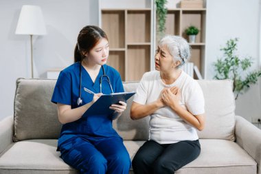 Doktor evdeki yaşlı hastayı muayene ediyor. Ellerinde pano tutan ve koltukta oturan yaşlı bir kadınla ilgilenen kadın terapist. Tıbbi servis kavramı