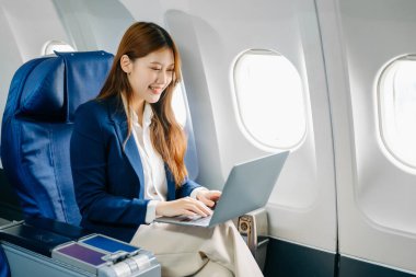 Genç Asyalı iş kadını dizüstü bilgisayar kullanarak uçakta birinci sınıfta. 