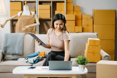 Genç işletme sahibi dizüstü bilgisayardaki müşteriye teslimat siparişlerini kontrol ediyor.