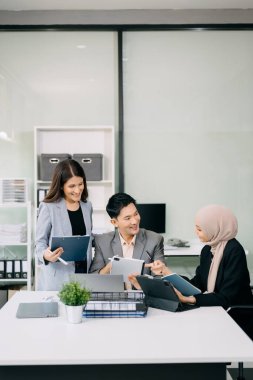 Bir grup Asyalı iş adamı yaratıcı iş planlaması için toplanıyor ofiste dijital tabletler kullanarak iş tartışıyorlar. 