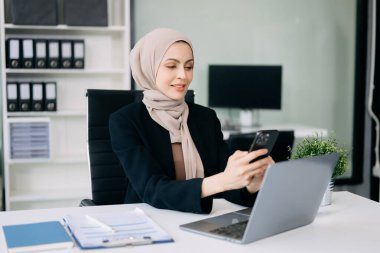 Ofiste çalışan ve akıllı telefon kullanan Arap iş kadını. 