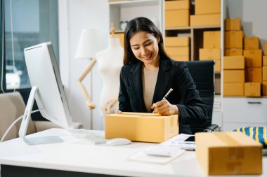 Genç işletme sahibi bilgisayarda müşteriye teslimat için online siparişleri kontrol ediyor