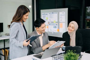 Bir grup Asyalı iş adamı yaratıcı iş planlama toplantısı ofiste dijital tabletler ve dizüstü bilgisayarlar kullanarak iş tartışması yapıyorlar.