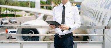 Üniformalı erkek pilotun orta kısmı uçağın dışında duruyor.