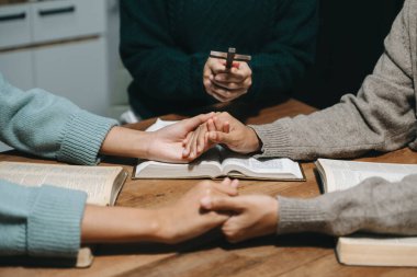 Bir grup Hıristiyan birlikte oturup ahşap bir masanın etrafında otururlar ve sınıfta bulanık incillerle dua ederler. Allah 'ın lütuf ve ihsanını dileyin..