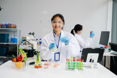 Asian female scientists conducting chemistry research in modern laboratory clipart