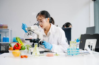 Asyalı kadın bilim adamları modern laboratuarda kimya araştırması yapıyorlar.