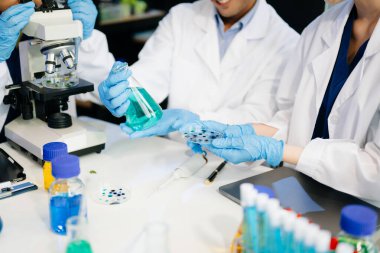 Bilim adamlarından oluşan bir ekibin laboratuvar ekipmanları, dizüstü bilgisayar ve dijital tabletlerle araştırma, test ve yenilikler üzerinde işbirliği yaptığı dinamik bilim laboratuvarı.