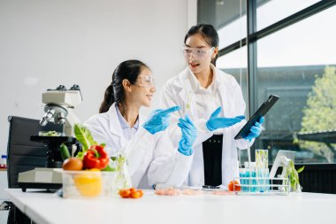 Asian female scientists conducting chemistry research in modern laboratory clipart