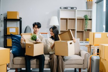 Karton paketli Asyalı genç ve çekici çift yeni eve taşınıyor.
