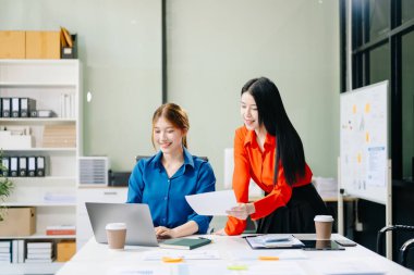 Asyalı iş arkadaşları dizüstü bilgisayar kullanıyor. Modern ofiste çalışan finansal pazarlama ekibi. 