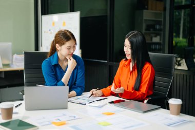 Asyalı iş arkadaşları dizüstü bilgisayar kullanıyor. Modern ofiste çalışan finansal pazarlama ekibi. 