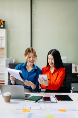 Asyalı iş arkadaşları dizüstü bilgisayar kullanıyor. Modern ofiste çalışan finansal pazarlama ekibi. 