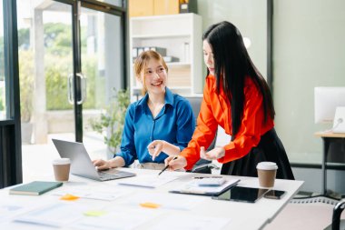 Asyalı iş arkadaşları dizüstü bilgisayar kullanıyor. Modern ofiste çalışan finansal pazarlama ekibi. 