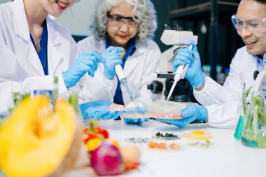 Laboratuvarda mikroskop ve pipetler kullanarak, örnekleri analiz ederek, yenilik, işbirliği ve gıda güvenliği araştırmalarını vurgulayarak yiyecek bilimcilerinin dinamik sahnesi