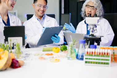 Laboratuvarda dizüstü bilgisayar, tablet, mikroskop ve pipetler kullanarak, örnekleri analiz ederek, yenilik, işbirliği ve gıda güvenliği araştırmalarını vurgulayarak yemek bilimcilerinin dinamik sahnesi