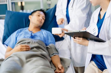 Profesyonel doktorlar bir hastayla konuşuyor, sağlık tavsiyesi veriyor, gelişmiş ekipmanlarla tedavi planı öneriyor. 