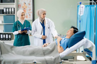 Hastane koğuşundaki bir hastayla ilgilenen doktorlar takım çalışması, profesyonellik ve sağlık hizmetleri sergiliyor.