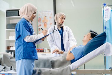 Hastane koğuşundaki bir hastayla ilgilenen doktorlar takım çalışması, profesyonellik ve sağlık hizmetleri sergiliyor.