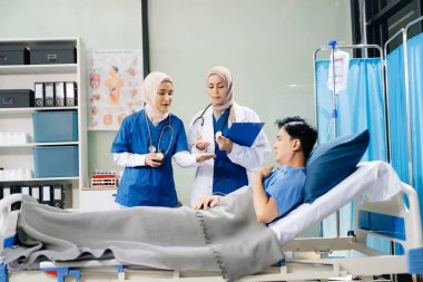 Hastane koğuşundaki bir hastayla ilgilenen doktorlar takım çalışması, profesyonellik ve sağlık hizmetleri sergiliyor.