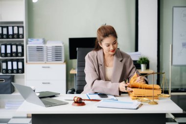 Modern ofiste hukuki analiz üzerinde çalışan kendine güvenen bir avukat, masada dizüstü bilgisayar kullanıyor.