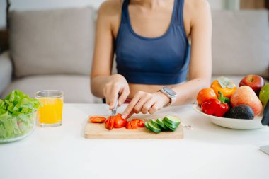 Formda bir kadının orta bölümü evde taze salata pişiriyor. Parlak, modern bir ev ortamında sağlığın, beslenmenin ve canlılığın vücut bulmuş hali. Sağlıklı bir yaşam tarzı!