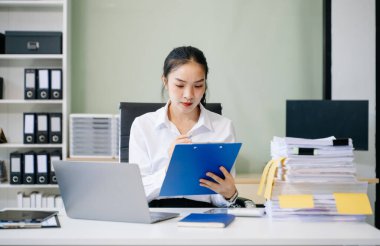 Genç Asyalı iş kadını çalıştığı yerde dizüstü bilgisayar kullanıyor. İşine odaklan.