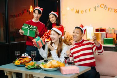 Asian friends capture the holiday spirit with gifts and a festive Christmas dinner in a cozy, joy-filled setting clipart