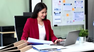 Genç Asyalı iş kadını ofiste dizüstü bilgisayarla çalışıyor.