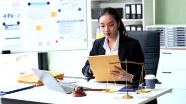 Dizüstü bilgisayarda çalışan profesyonel kadın avukat ve masa başında çalışan belgeler, tokmak, adalet terazisi ve canlı bir hukuk bürosu ortamı içeriyor.   