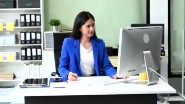 Ofiste bilgisayarla çalışan Asyalı genç bir iş kadını.