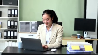 Modern ofis masasında dizüstü bilgisayarda çalışan başarılı Asyalı iş kadını