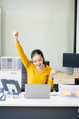 Modern ofis masasında başarılı bir Asyalı iş kadını dijital tablet ve laptop üzerinde çalışıyor.