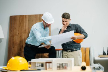 Mimarlar ve tasarımcılar modeller ve planlar üzerinde işbirliği yapıyorlar, yenilikçi yapılar üzerinde beyin fırtınası yapıyorlar ve modern bir ofiste kentsel gelişim planlıyorlar..
