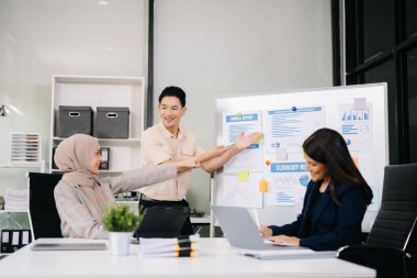 Ofiste beyin fırtınası yaparken dizüstü bilgisayar ve tablet kullanan iş adamları yeni bir projede işbirliği yapıyorlar