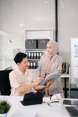 Ofiste beyin fırtınası yaparken dizüstü bilgisayar ve tablet kullanan iş adamları yeni bir projede işbirliği yapıyorlar