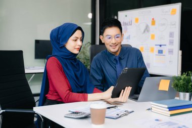 Ofiste beyin fırtınası yaparken dizüstü bilgisayar ve tablet kullanan iş adamları yeni bir projede işbirliği yapıyorlar